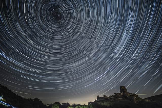 Satellites, planes and comets transit across the night sky under stars that appear to rotate above Corfe Castle (Photo: Dan Kitwood/Getty Images)