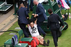LONDON, ENGLAND - JULY 05: A protester is dragged off by security on court 18 after a Just Stop Oil protest using orange confetti and a jigsaw puzzle during the Women's Singles first round match between Katie Boulter of Great Britain and Daria Saville of Australia during day three of The Championships Wimbledon 2023 at All England Lawn Tennis and Croquet Club on July 05, 2023 in London, England. (Photo by Julian Finney/Getty Images)