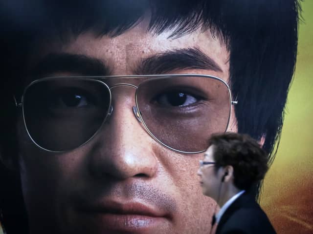 A woman walks in front of a poster featuring kung fu action hero Bruce Lee at a museum in Hong Kong on November 3, 2018. - Raymond Chow, the film producer credited with bringing kung fu legend Bruce Lee to the silver screen and widely regarded as the godfather of Hong Kong cinema, has died aged 91, reports said Saturday. (Photo by VIVEK PRAKASH / AFP)        (Photo credit should read VIVEK PRAKASH/AFP via Getty Images)