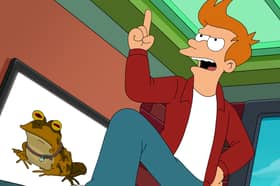 Billy West as Philip J Fry in Futurama S11, stood on his desk dramatically, an image of Hypnotoad on the wall-mounted television behind him (Credit: Hulu)