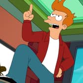 Billy West as Philip J Fry in Futurama S11, stood on his desk dramatically, an image of Hypnotoad on the wall-mounted television behind him (Credit: Hulu)