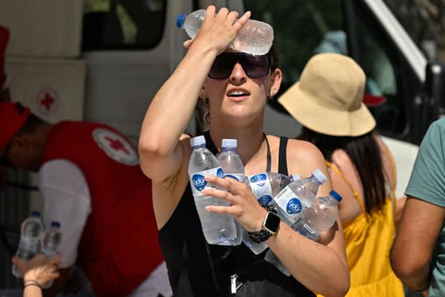 A woman cools off with cold bottles of water in Athens on July 20, as Greece dealt with a new major heatwave (Photo by LOUISA GOULIAMAKI/AFP via Getty Images)