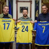 Oleksandr Zinchenko, Volodymyr Zelensky, and Andriy Shevchenko, holding up football shirts (Credit: United24)