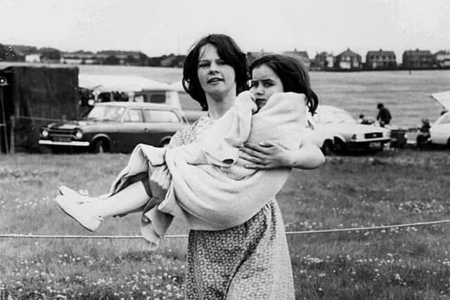 A woman carries a child at Hollinwell Showground, July, 1980 (Copyright: Neil Lancashire)