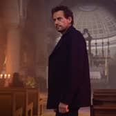 Ioan Gruffudd as Thomas in The Reunion, stood in a dimly-lit church (Credit: ITV)