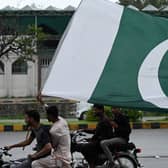 A man waves Pakistan's national flag as he rides a bike in Islamabad on August, 14, 2023, celebrating the country's Independence Day. (Photo by AAMIR QURESHI/AFP via Getty Images)