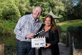 Alan Fletcher and Rebekah Elmaloglou behind the scenes filming Neighbours, holding a clapperboard that reads "day one" (Credit: Ray Messner)