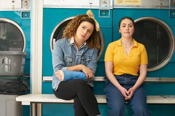 Rose Matafeo as Jessie and Emma Sidi as Kate in Starstruck, sat in front of a row of washing machines (Credit: BBC/Avalon UK)