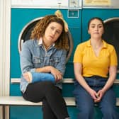 Rose Matafeo as Jessie and Emma Sidi as Kate in Starstruck, sat in front of a row of washing machines (Credit: BBC/Avalon UK)