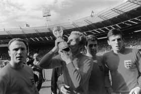Bobby Moore (1941 - 1993), England captain, kisses the Jules Rimet World Cup trophy after England's 4-2 win over West Germany in the World Cup final at Wembley. Team-mates George Cohen, Geoff Hurst and Martin Peters join Moore in a victory lap.  (Photo by Fox Photos/Getty Images)