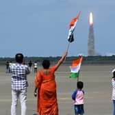 People wave Indian flags as an Indian Space Research Organisation (ISRO) rocket carrying the Chandrayaan-3 spacecraft lifts off from the Satish Dhawan Space Centre in Sriharikota, an island off the coast of southern Andhra Pradesh state on July 14, 2023. (Image: Photo by R.SATISH BABU/AFP via Getty Images)