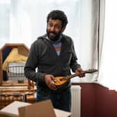 Adeel Akhtar as Billy in Back to Life, holding a small guitar (Credit: BBC/Two Brothers Pictures/Luke Varley)