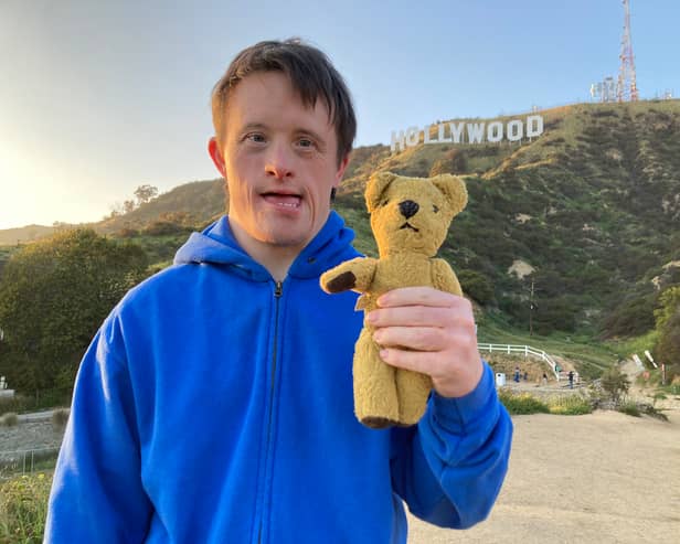 Tommy Jessop and his teddy Roger in Tommy Jessop Goes to Hollywood, stood in front of the Hollywood sign (Credit: BBC)
