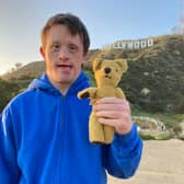 Tommy Jessop and his teddy Roger in Tommy Jessop Goes to Hollywood, stood in front of the Hollywood sign (Credit: BBC)