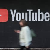 A young woman with a smartphone walks past a billboard advertisement for YouTube (Image: Sean Gallup/Getty Images)