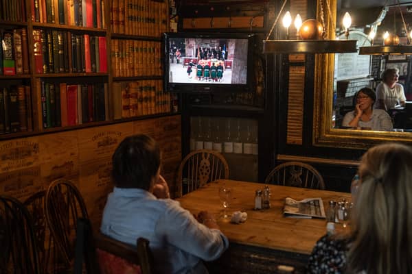 People watch on a television in a pub as the coffin carrying Queen Elizabeth II arrives at St Giles' Cathedral in Edinburgh on 12 September 2022 (Photo: Carl Court/Getty Images)