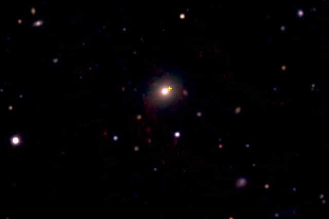 Undated handout photo issued by Queen's University Belfast of an image from the European Southern Observatory New Technology Telescope showing a distant red galaxy (centre) where a cosmic explosion occurred. The explosion site is marked by the yellow cross (Image:Queen's University Belfast/ PA)