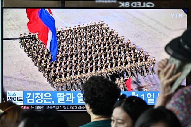 People in South Korea sit in front of a television showing a news broadcast with a photo of a parade marking the 75th anniversary of North Korea's founding. Credit: ANTHONY WALLACE/AFP via Getty Images