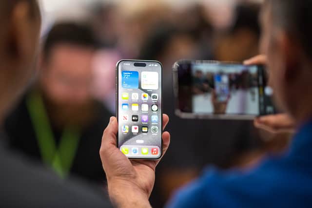 A person looks at an Apple iPhone 15 Pro during a launch event at Apple Park in Cupertino, California, on September 12, 2023. (Photo by NIC COURY/AFP via Getty Images)