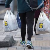 A person leaves with their goods in plastic carrier bags after shopping at a branch of Lidl in south London.