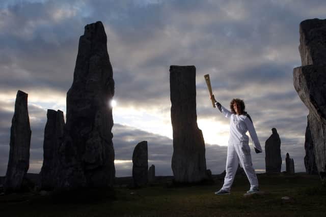 Torchbearer 003 Kirsty Wade holds the Olympic Flame at the Calanais Standing Stones in Callanish as the sun rises on day 24 of the London 2012 Olympic Torch Relay on June 11, 2012 in Lewis, Scotland.  (Photo by LOCOG via Getty Images)