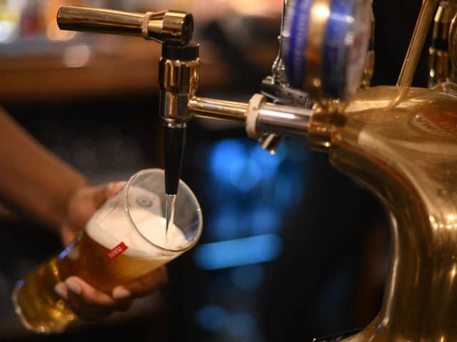 An employee pours a pint of Peroni beer on at the bar in the Mad Hatter pub and hotel in London. (Photo by DANIEL LEAL/AFP via Getty Images)