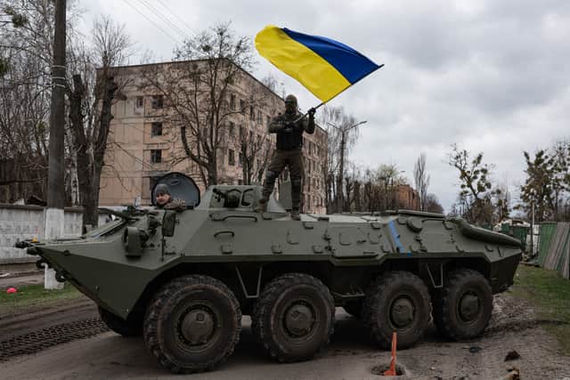 HOSTOMEL, UKRAINE - APRIL 08: Ukrainian soldier waves Ukrainian national flag while standing on top of an armoured personnel carrier (APC). (Photo by Alexey Furman/Getty Images)