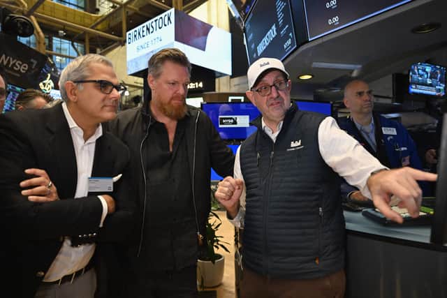 Birkenstock CEO Oliver Reichert (C) and Managing Partner at L Catterton Nik Thukral (L) listen to specialist Peter Giacchi on the trading floor at the New York Stock Exchange (NYSE) in New York on October 11, 2023, during Birkenstock's launch of an Initial Public Offering (IPO). (Photo by ANGELA WEISS/AFP via Getty Images)