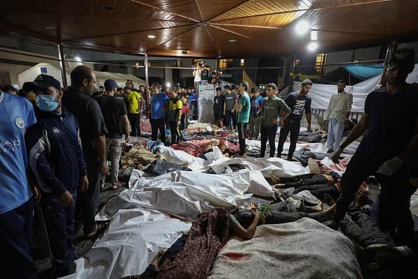 People gather around bodies of Palestinians killed after a strike ripped through the Ahli Arab hospital in central Gaza after they were transported to Al-Shifa hospital, on October 17, 2023.(Photo by DAWOOD NEMER/AFP via Getty Images)