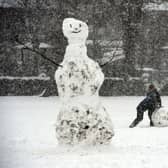 A boy rolls a giant snow ball near a snowman in Victoria Park in Glasgow on February 9, 2021. - Cold weather swept across northern Europe bring snow and ice. (Image: ANDY BUCHANAN/AFP via Getty Images)