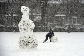 A boy rolls a giant snow ball near a snowman in Victoria Park in Glasgow on February 9, 2021. - Cold weather swept across northern Europe bring snow and ice. (Image: ANDY BUCHANAN/AFP via Getty Images)