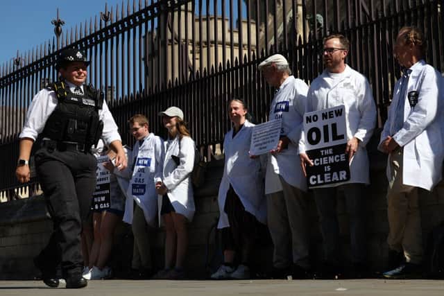 A police officer passes demonstrators, including scientists and doctors, calling for the government to stop awarding new licences for oil and gas production in the UK (Photo by ADRIAN DENNIS/AFP via Getty Images)