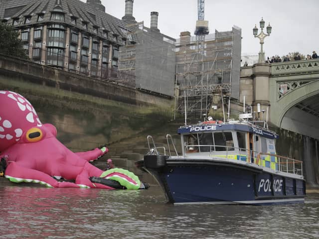 A police boat checks out the 20-metre tall octopus in the Thames (Photo: Kristian Buus / Greenpeace)