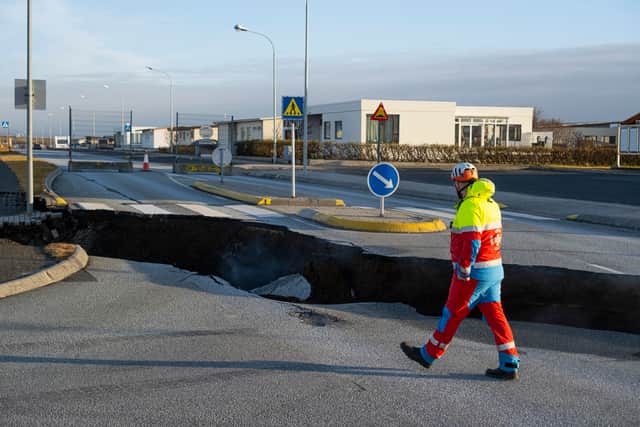 A member of the emergency services walking near a crack cutting across the main road in Grindavik (Photo: KJARTAN TORBJOERNSSON/AFP via Getty Images)