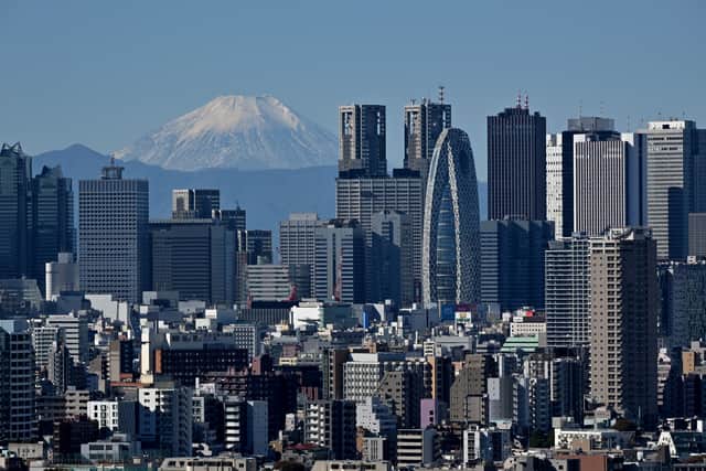 This picture taken on November 14, 2023 shows Japan's highest mountain, Mt. Fuji in the background between skyscrapers in Tokyo's Shinjuku area. (Photo by Kazuhiro NOGI / AFP) 