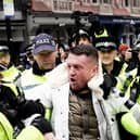 Tommy Robinson is led away by police officers as people take part in a march against antisemitism organised by the volunteer-led charity Campaign Against Antisemitism at the Royal Courts of Justice in London. (Image: PA)