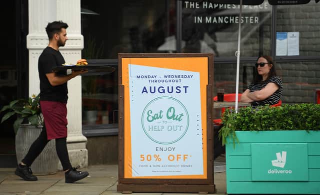 A server carries food past a sign promoting the British Government's "Eat out to Help out" (OLI SCARFF/AFP via Getty Images)