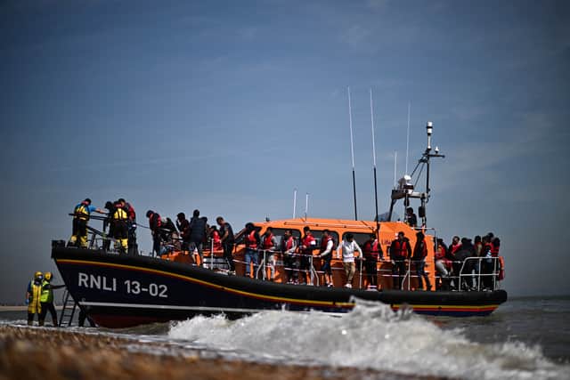 Migrants, picked up at sea attempting to cross the English Channel, are helped ashore from an Royal National Lifeboat Institution's (RNLI) lifeboat at Dungeness on the southeast coast of England, on June 15, 2022