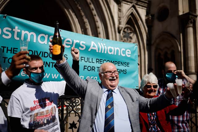 Former subpostmaster at Hogsthorpe, Tom Hedges (C) holds a bottle of champagne aloft outside the Royal Courts of Justice in London, on April 23, 2021, following a court ruling clearing subpostmasters of convictions for theft and false accounting. - Dozens of former subpostmasters, who were convicted of theft, fraud and false accounting because of the Post Office's defective Horizon accounting system, have finally had their names cleared by the Court of Appeal. (Photo by Tolga Akmen / AFP)