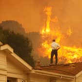 A man on a rooftop looks at approaching flames (Photo: David McNew/Getty Images)