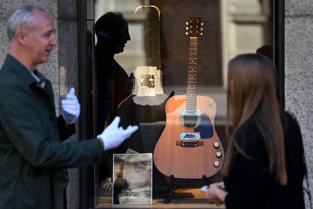 Co-owner of Julien's Auctions, Martin Nolan chats to a passer-by about the guitar used by musician Kurt Cobain during Nirvana's famous MTV Unplugged in New York concert in 1993, displayed in the window of the Hard Rock Cafe Piccadilly Circus in central London on May 15, 2020, prior to the auction of the guitar in Beverly Hills in June. Picture: Getty
