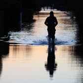 A yellow warning for rain has been issued by the Met Office and travel disruption is to be expected. People walk through floodwater on a flooded street in Wraysbury, west of London on January 9, 2024, after heavy rain brought flooding to much of the country following Storm Henk. (Photo by DANIEL LEAL/AFP via Getty Images)