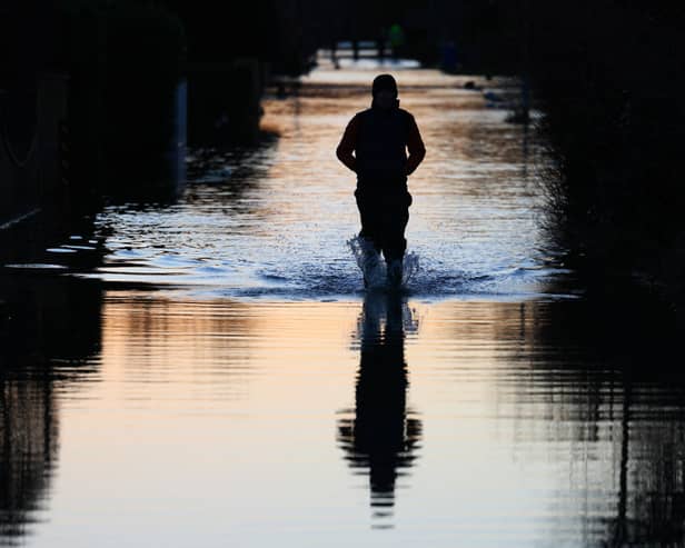 A yellow warning for rain has been issued by the Met Office and travel disruption is to be expected. People walk through floodwater on a flooded street in Wraysbury, west of London on January 9, 2024, after heavy rain brought flooding to much of the country following Storm Henk. (Photo by DANIEL LEAL/AFP via Getty Images)