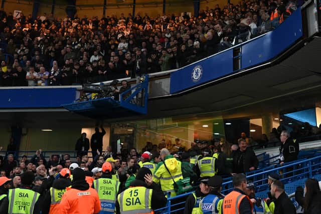 A Leeds fan is taken away by medical teams after falling from the upper tier at Stamford Bridge.