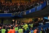 A Leeds fan is taken away by medical teams after falling from the upper tier at Stamford Bridge.