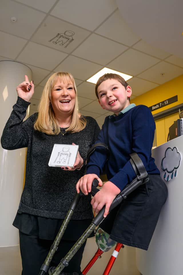 Nine-year-old Tony Hudgell, right, stands underneath his commemorative ceiling tile - which depicts him as an astronaut on his crutches. (Picture: David Tett/Guy's and St Thomas' NHS Foundation Trust/PA Wire)