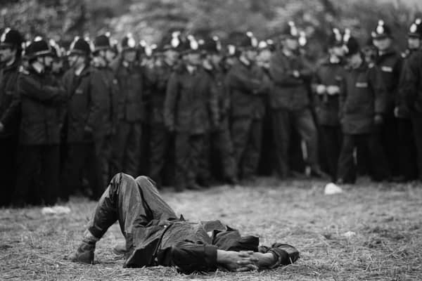 View of a striking miner as he lays on the ground in front of a line of police officers  near the Orgreave coking plant, Orgreave
