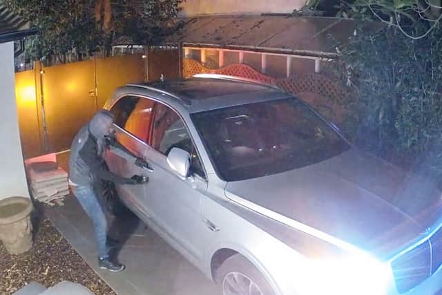 In footage released by Surrey Police, one thief is seen using a device to unlock a keyless vehicle after “hacking” into it, before ramming it through a gated driveway. (Photo: Surrey Police / SWNS)