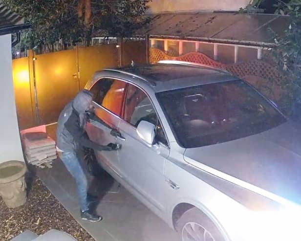 In footage released by Surrey Police, one thief is seen using a device to unlock a keyless vehicle after “hacking” into it, before ramming it through a gated driveway. (Photo: Surrey Police / SWNS)