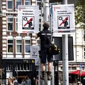 A municipal worker hangs a prohibition sign in the Nieuwmarkt publicising the new legislation forbidding the smoking of cannabis in public in the old city centre of Amsterdam on May 23, 2023. (Photo by Ramon van Flymen / ANP / AFP) 